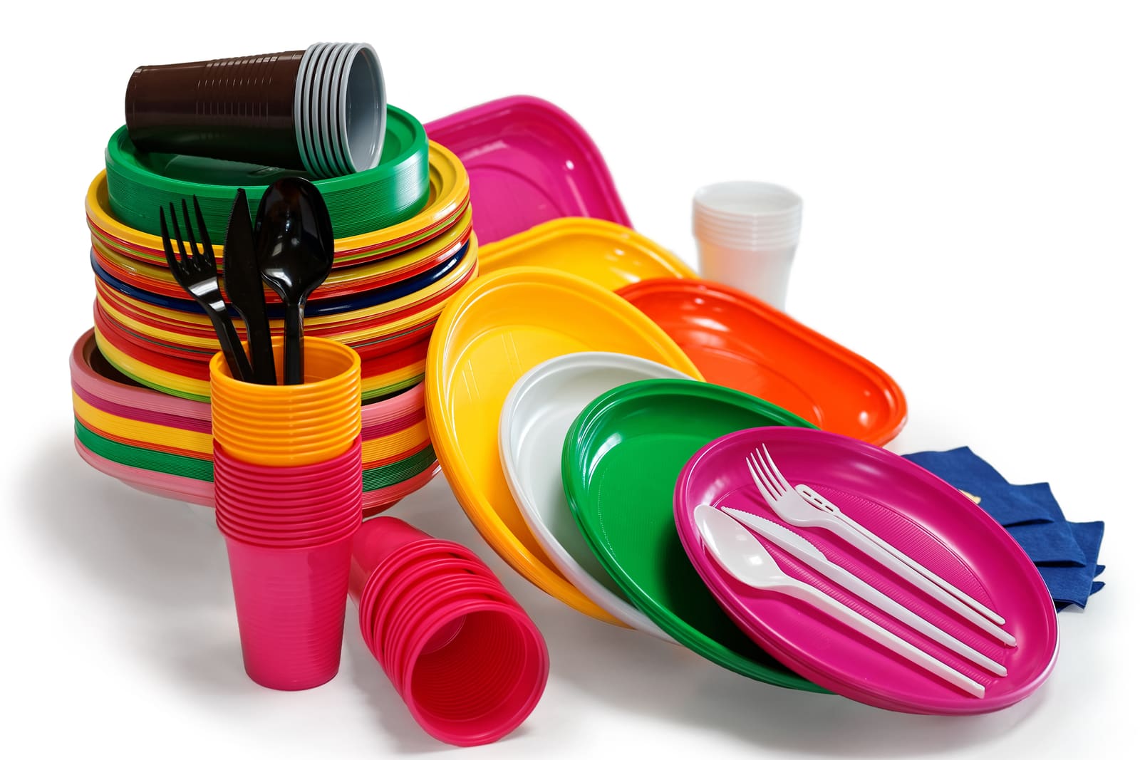 Stacks of colourful disposable plastic plates, cups and cutlery