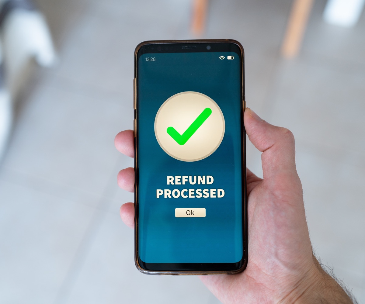 A customer holding a phone showing that a refund has been processed
