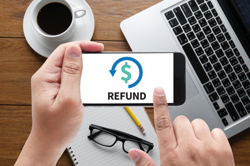 Phone displaying a refund symbol beside a laptop
