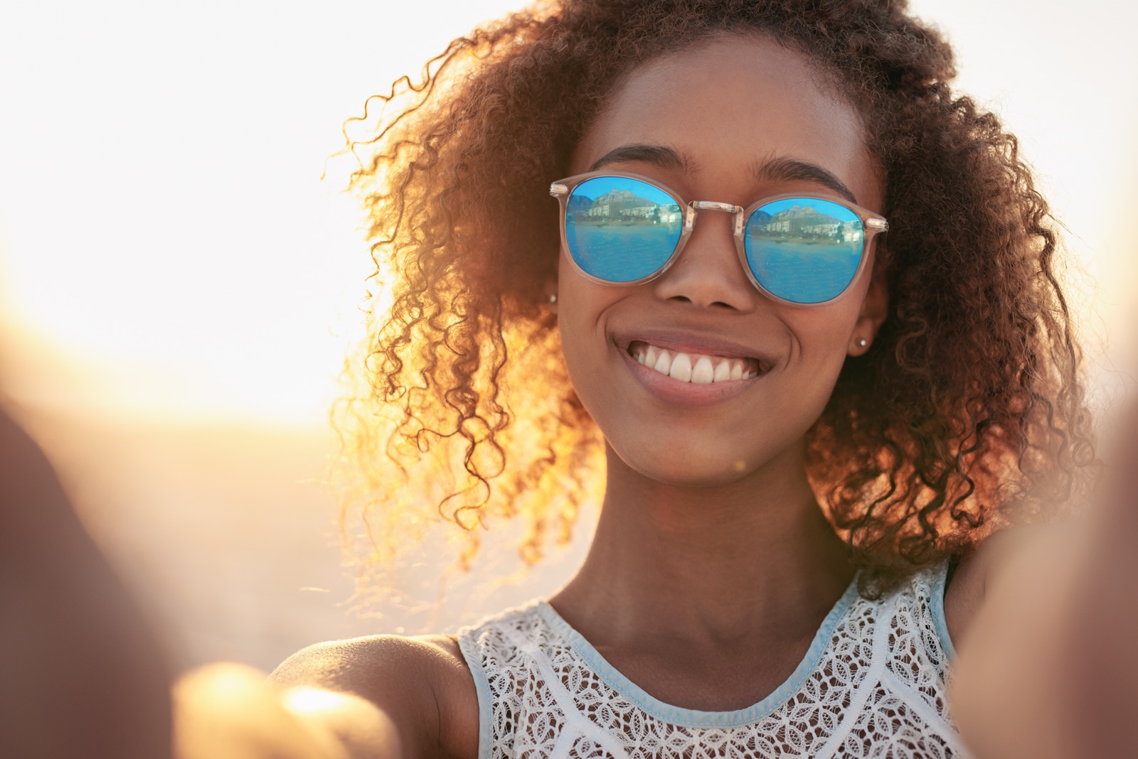 Person wearing blue mirrored sunglasses in bright summer sunlight